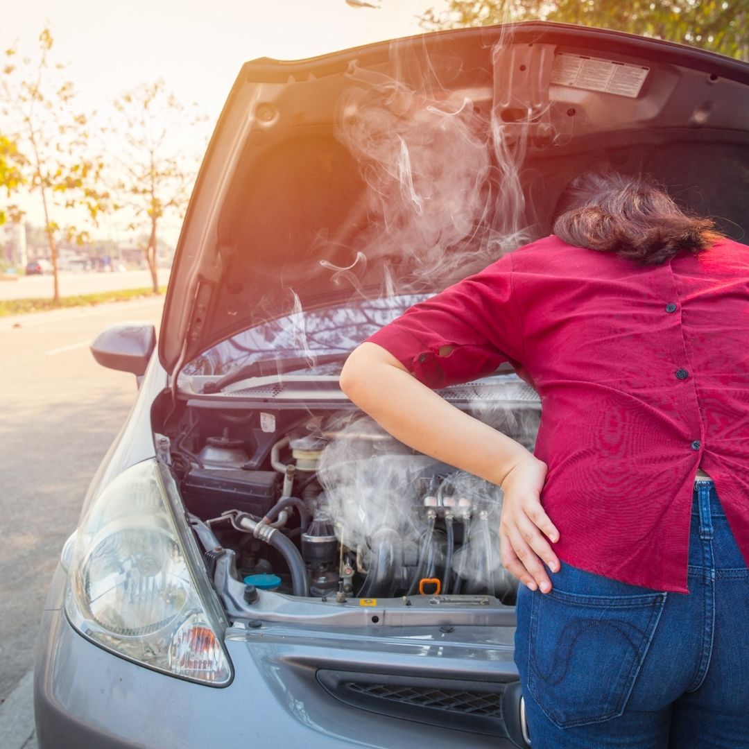 Woman looking at car engine smoking
